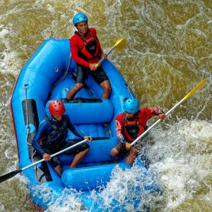 Exciting rafting adventure with a team navigating rapids in Cikidang, West Java. Enthusiastic paddlers in an inflatable blue raft.